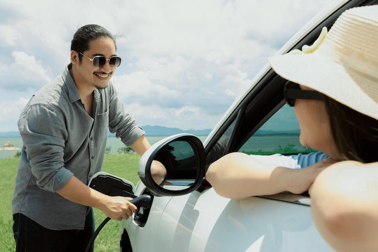 Pasangan menggunakan mobil listrik